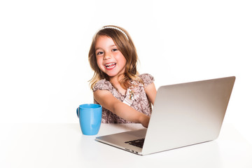 cheerful Little girl uses laptopon a white background, space for text