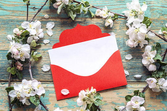 Red envelope with apple blossom on old wooden background. Space for text.