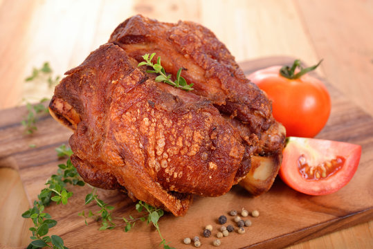 pork knuckle or German pork hocks on chopping board and on wooden table