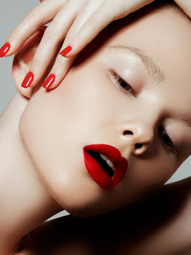 Fototapeta Beautiful woman with red matte lipstick. Beautiful woman face. Makeup detail. Beauty girl with perfect skin. Red lips and nails manicure