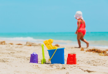kids toys and little girl playing on beach