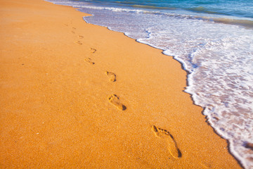 beach, wave and footprints at sunset time