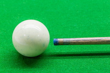 Close up white ball dirty blue chalk powder and cue on green table, billiard playing.