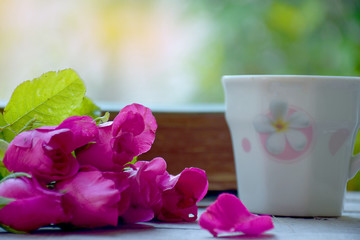 Beautiful pink rose with cup of coffee on the wooden