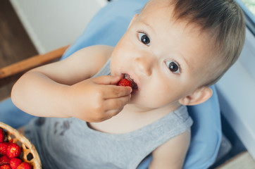 the child in the kitchen eating strawberries