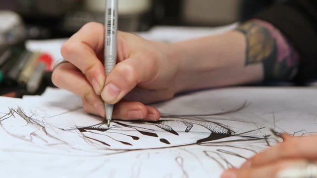 Girl tattoo artist draws a sketch. Close-up of hands