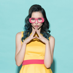 Portrait of a beautiful woman in paper glasses on a blue background.