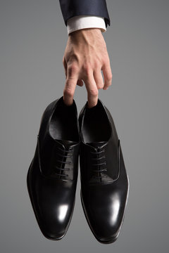 Businessman holding luxury leather shoes in hand. Close-up.