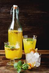 Alcoholic cocktail with fresh passion fruit with mint and ice. Dark wood background.