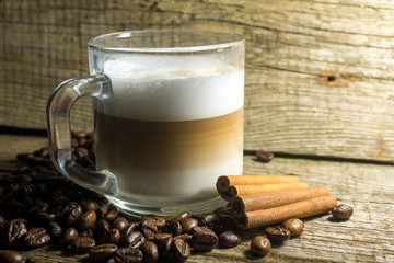 Cup of cappuccino and grain of coffee over wooden background