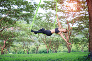 young asian woman aerial yoga fitness practice outdoor on the tree forest