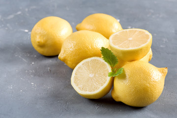 Lemons on cutting board on grey background Fresh yellow citrus Mint leaf