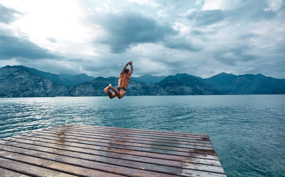 man jumping into the water from the pier. Lago di Garda lake, Italy