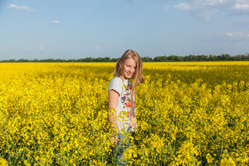 Naklejka na ściany i meble children in the field with the flowering yellow flowers of rape