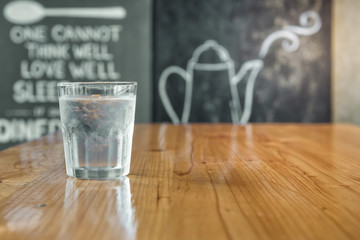 A glass of water is placed on the wood table.