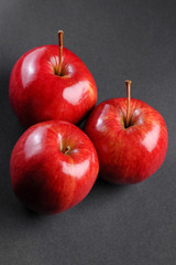 Three red apples on black background
