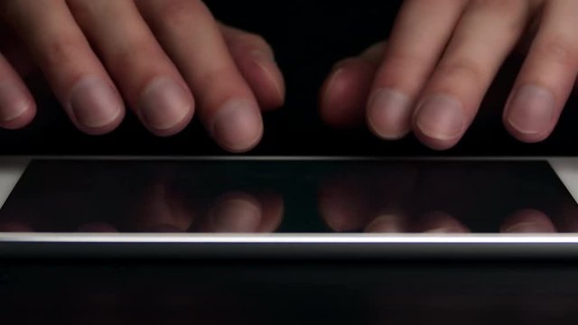Man types text message on electronic tablet. Hands close-up.
