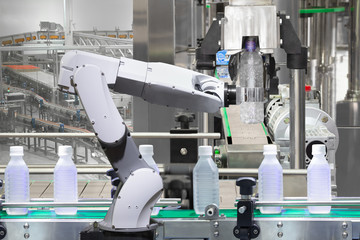Robotic arm holding water bottles on drink production line in factory, Industry 4.0 concept