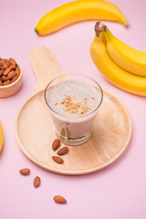 Fresh made banana smoothie in a glass on pink background