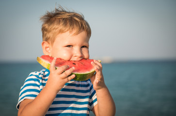 Caucasian boy eating watermelon on beach