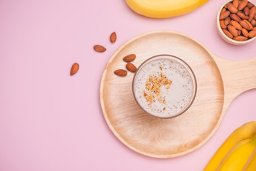 Fresh made banana smoothie in a glass on pink background