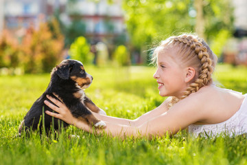 Little girl with a berner sennenhund puppy, outdoor, summer