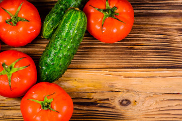 Ripe tomatoes and cucumbers on wooden table. Top view
