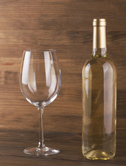 White wine bottle and a glass placed on wooden table. Copy space. Vertical studio shot