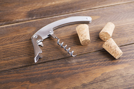 Close-up of corkscrew next to several corks. Horizontal studio shot.