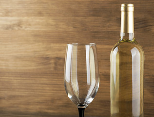 White wine bottle and a glass placed on wooden table. Copy space. Horizontal studio shot. Copy space.