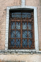 Деревянное коричневое окно за фигурной решёткой на кирпичной стене