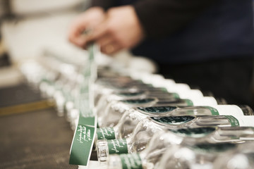 Close up of a man labeling glass bottles in a beer brewery or distillery.