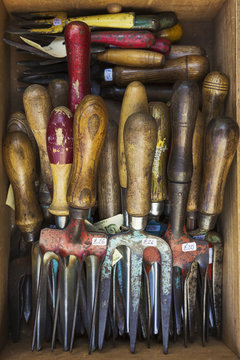 Overhead view of a collection of handheld garden forks, with metal tines and smooth wooden handles. 