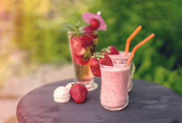 Breakfast banana smoothie strawberry detox drink of strawberries and mint with marshmallows on a green plant background.