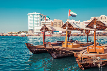 Fototapeta premium Piers of traditional water taxi boats in Dubai, UAE. Panoramic view on Creek gulf and Deira area. Creative color post processing. United Arab Emirates famous tourist destination