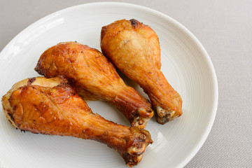 grilled chicken drumstick on a white dish with grey fabric background