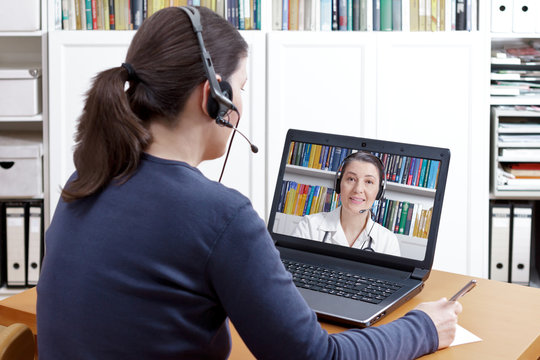 Woman with headset in front of her computer making a video call with her doctor, e-health, telehealth or telemedicine concept.