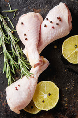 Chicken legs with rosemary, pepper and lemon. Dark background. Lunch on the grill. Space for text. Top view