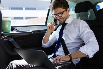 Smiling businessman with phone in car