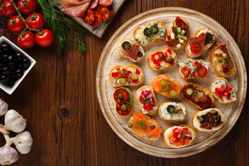 Crostini with different toppings on wooden background. Delicious appetizers. Top view.