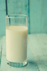 Glass of milk on wooden table and lactose free sign, on bricks wall background