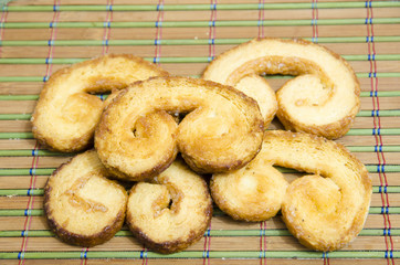 
Sweet ears from puff pastry lie on a bamboo mat.