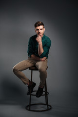 Concentrated young man sitting isolated over grey background