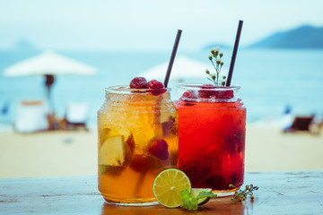 Close up of two glasses with refreshing strawberry cocktail with lime, apple and mint on sea beach...