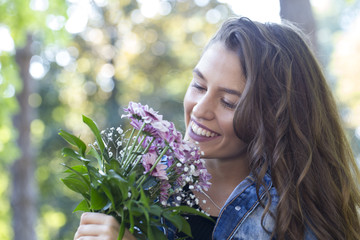Fototapeta premium Portrait of a beautiful young woman holding flowers in her hand