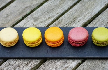 Colorful round macaron cookies on a black slate platter
