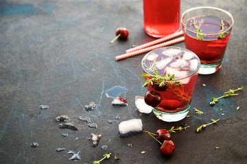 Homemade cherry lemonade with thyme on a dark blue background 
