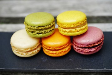 Colorful round macaron cookies on a black slate platter