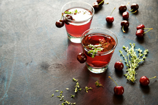 Homemade cherry lemonade with thyme on a dark blue background 
