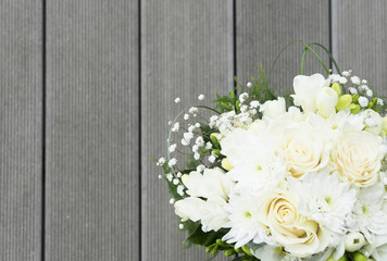 white fresh roses, freesia and mum flowers wedding bouquet on wooden background